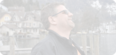 Michel Streiff steht voller Selbstvertrauen am See und blickt in den Himmel.