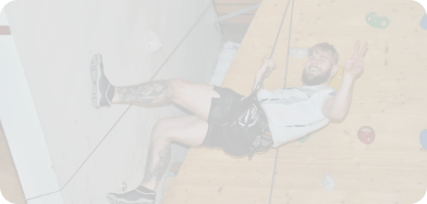 Ein Teilnehmer hängt an einer Indoor-Kletterwand. Er freut sich über seinen Erfolg.