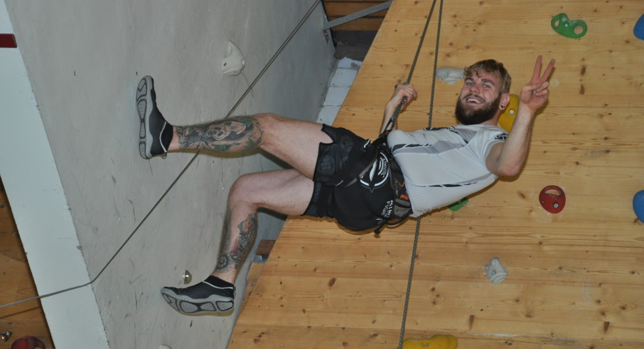 Kletterwand_lifeenergy_6_2019.JPG Ein Teilnehmer hängt an einer Indoor-Kletterwand. Er freut sich über seinen Erfolg.